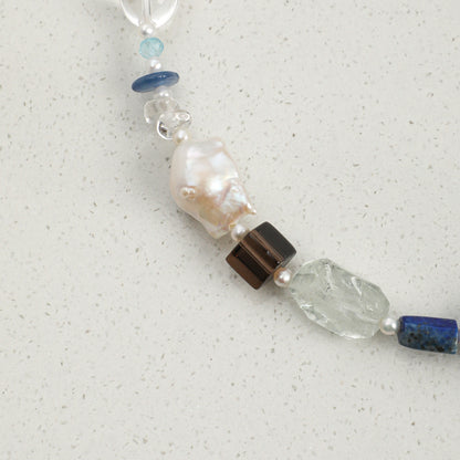 Lapis lazuli necklace detail: pearl and blue stones with a clear faceted crystal segment