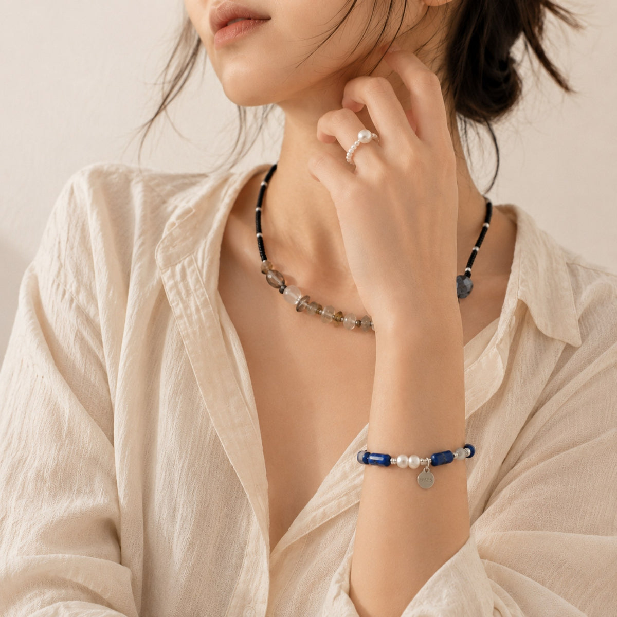 Woman wearing a necklace and bracelet with a neutral background