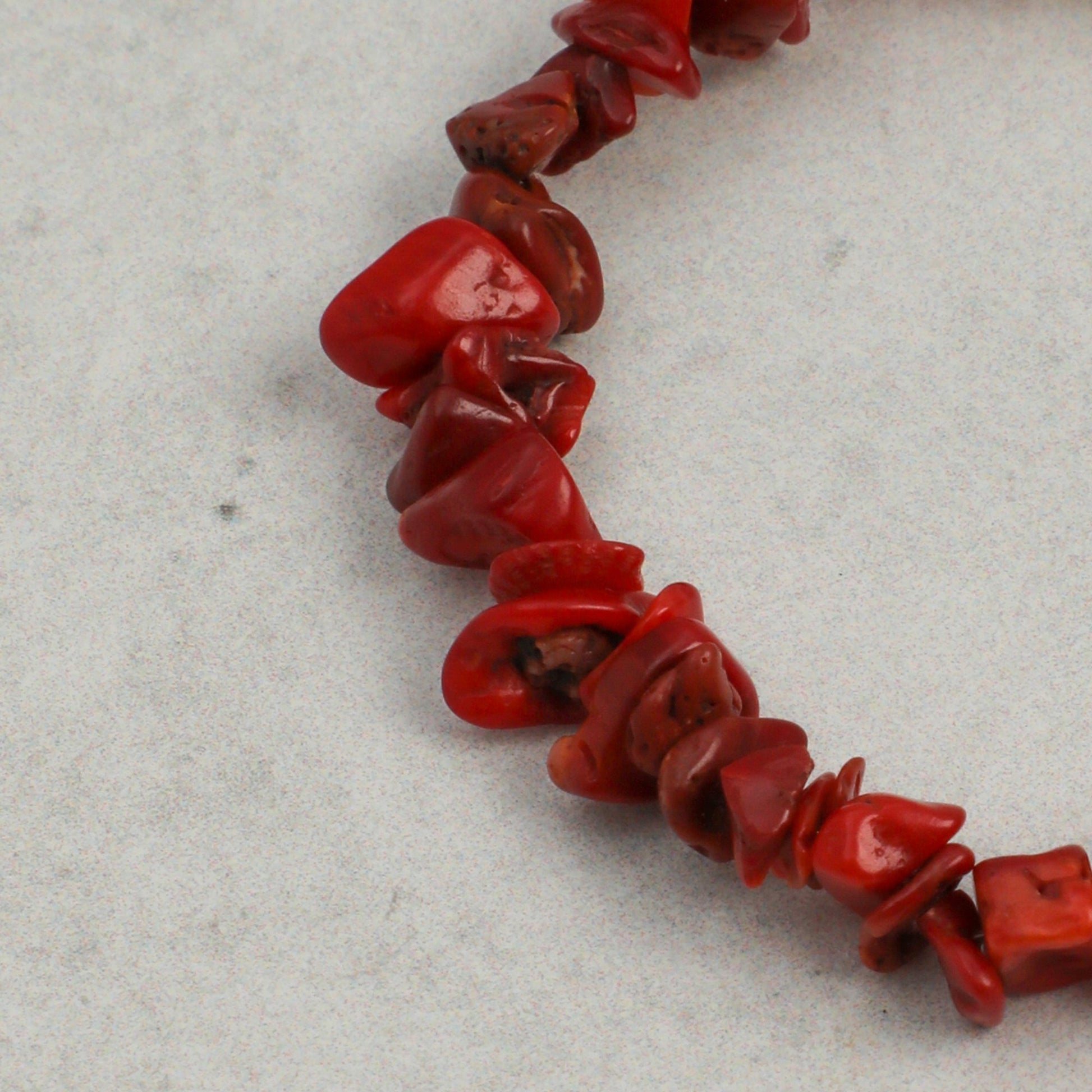 Red bead bracelet segment with glossy chip beads and curved links