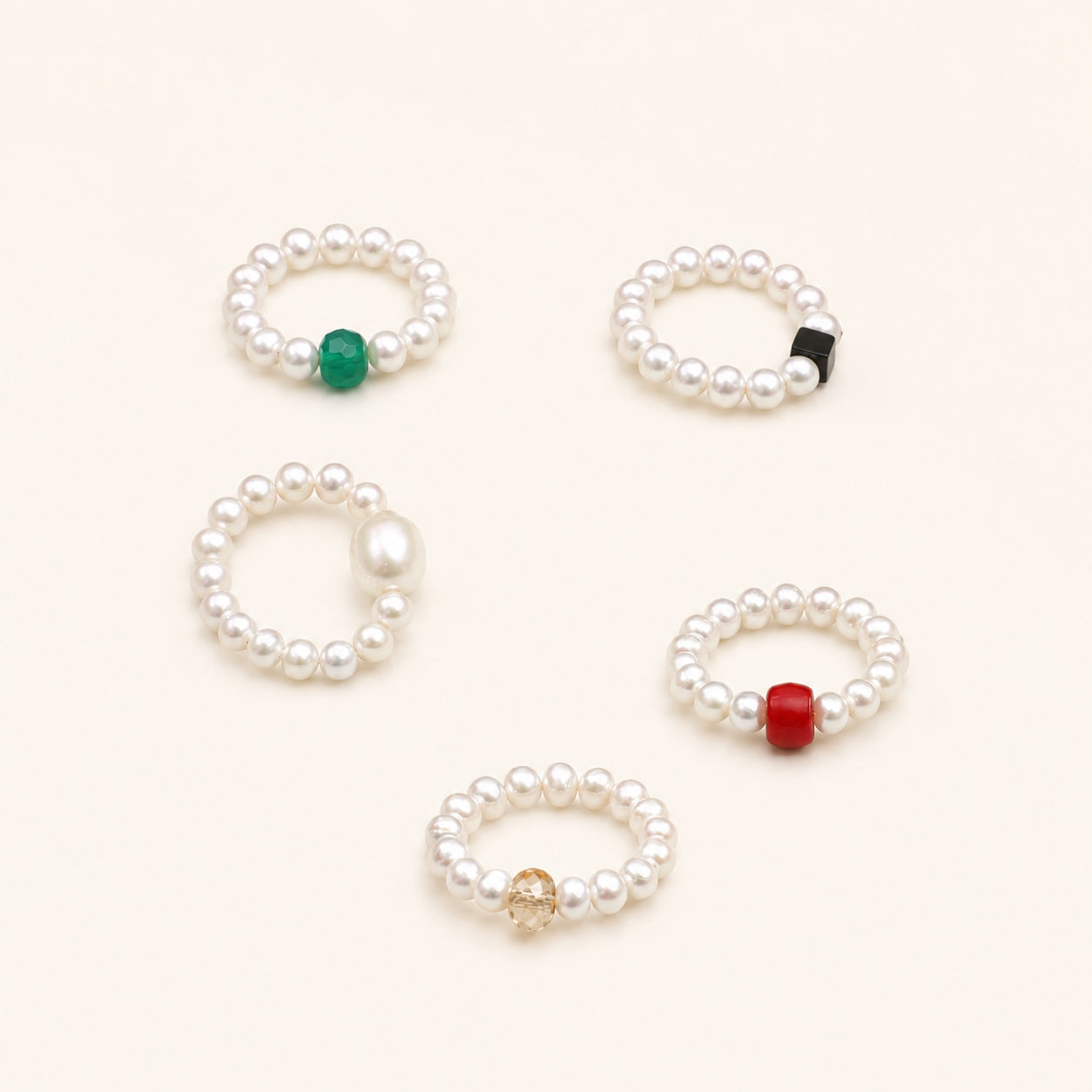 Set of five pearl beaded rings with green, black, gold, and red accents