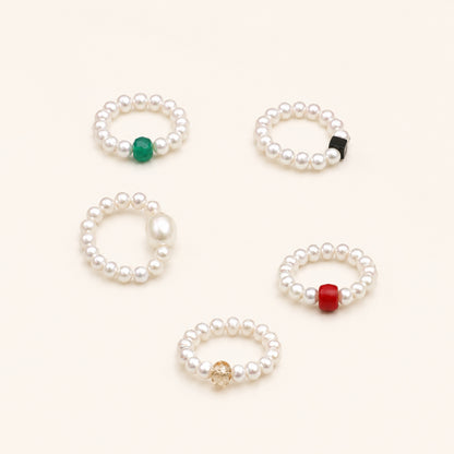 Set of five pearl beaded rings with green, black, gold, and red accents
