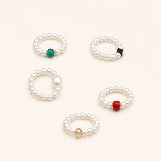 Set of five pearl beaded rings with green, black, gold, and red accents