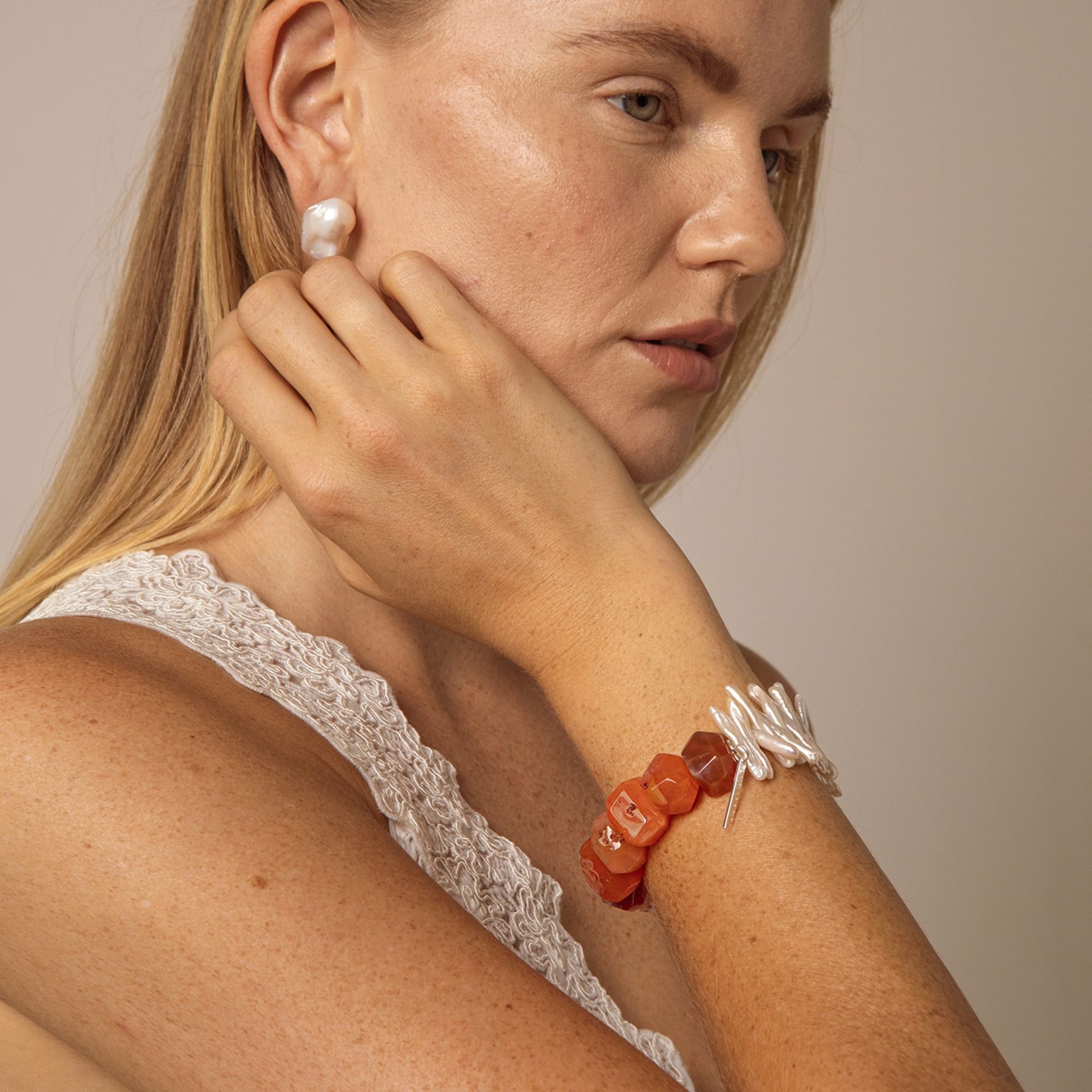 Bracelet on wrist with orange agate beads and white pearl-like accents