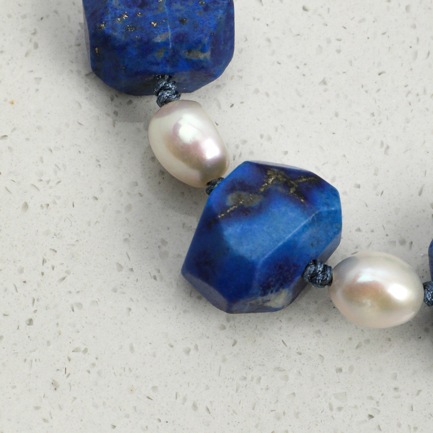 Lapis lazuli and pearl bracelet featuring faceted blue stones and cream pearls on cord