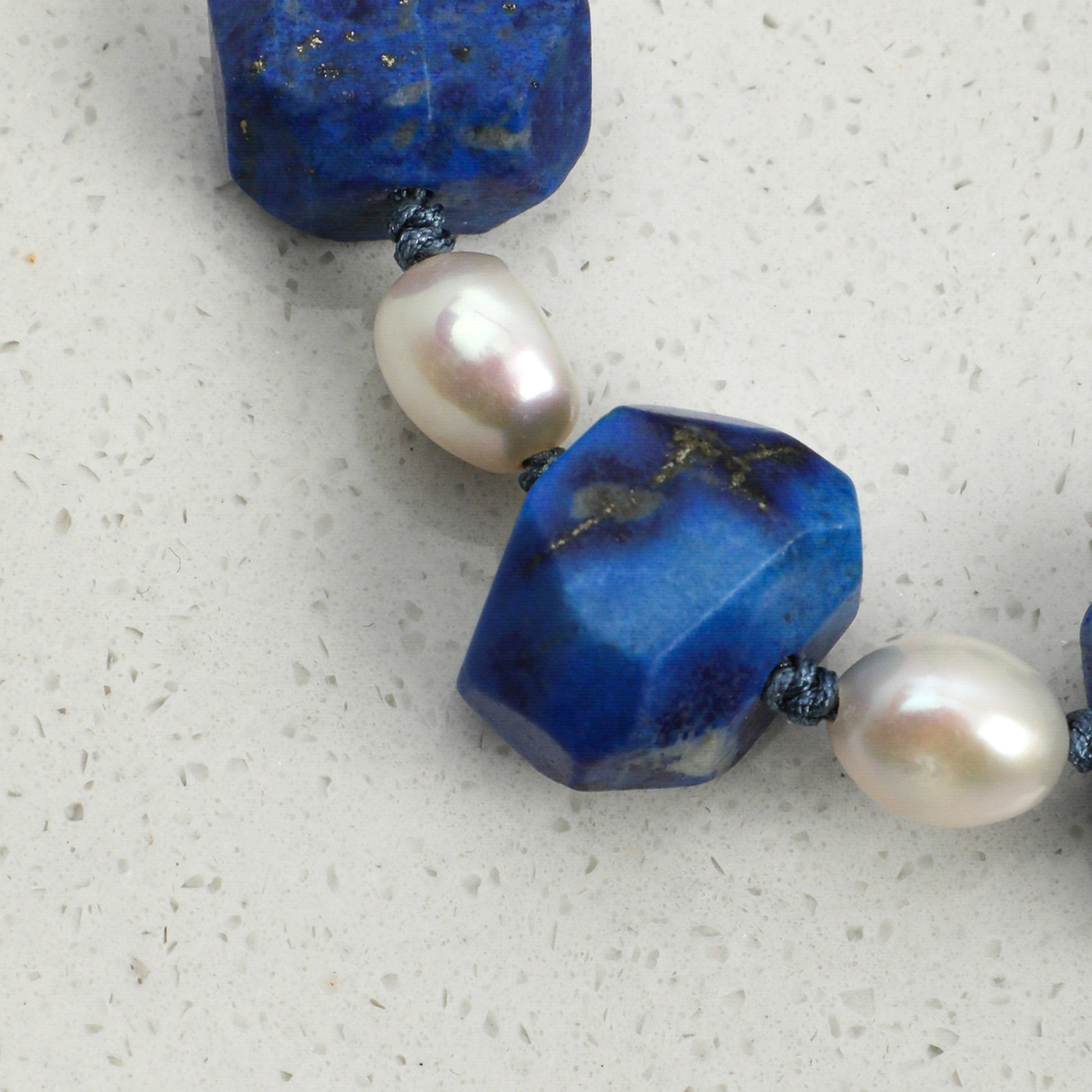 Lapis lazuli and pearl bracelet featuring faceted blue stones and cream pearls on cord