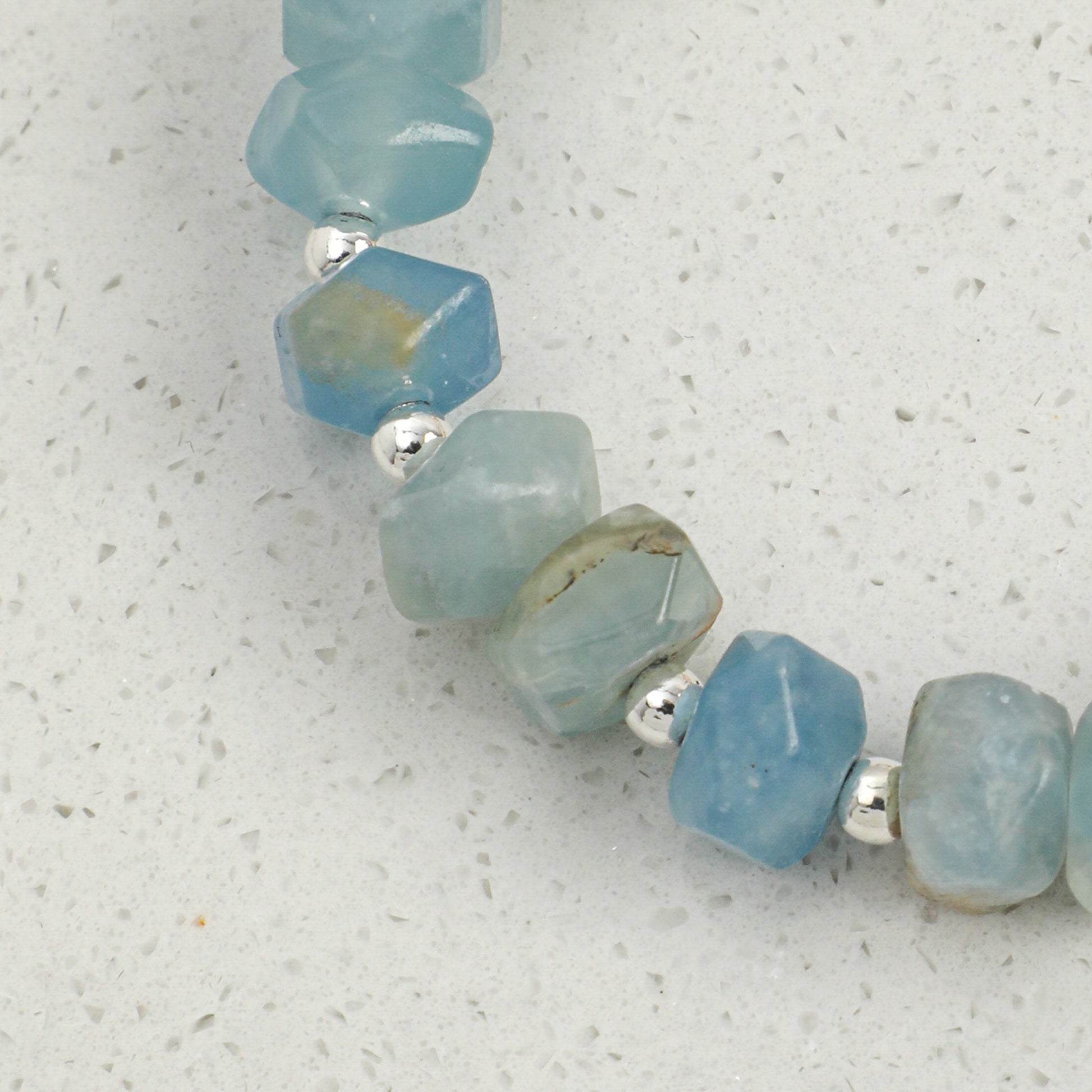 Faceted blue gemstone beads with silver links on a pearl bracelet