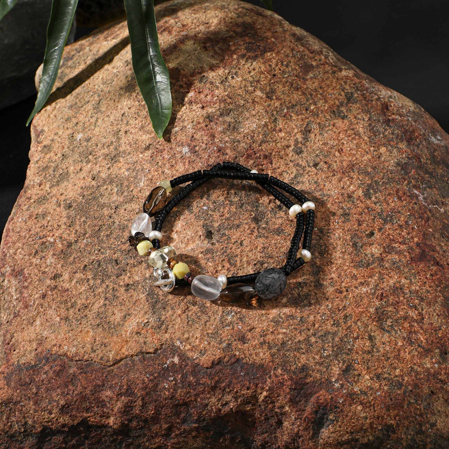 Black cord necklace with mixed clear, smoky grey, and gold-tone beads with small pearls