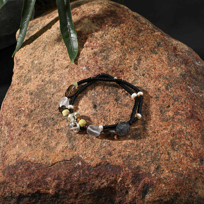 Black cord necklace with mixed clear, smoky grey, and gold-tone beads with small pearls