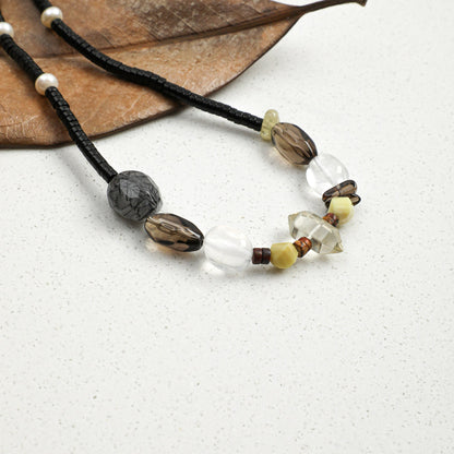 Black cord necklace with grey stones, white crystals, and gold-tone bead accents