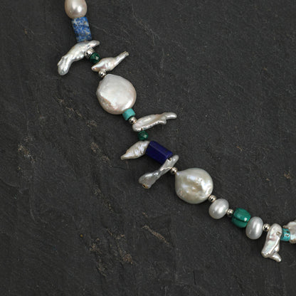 Baroque pearl necklace with silver bird charms, lapis blue bead, and teal-green stones